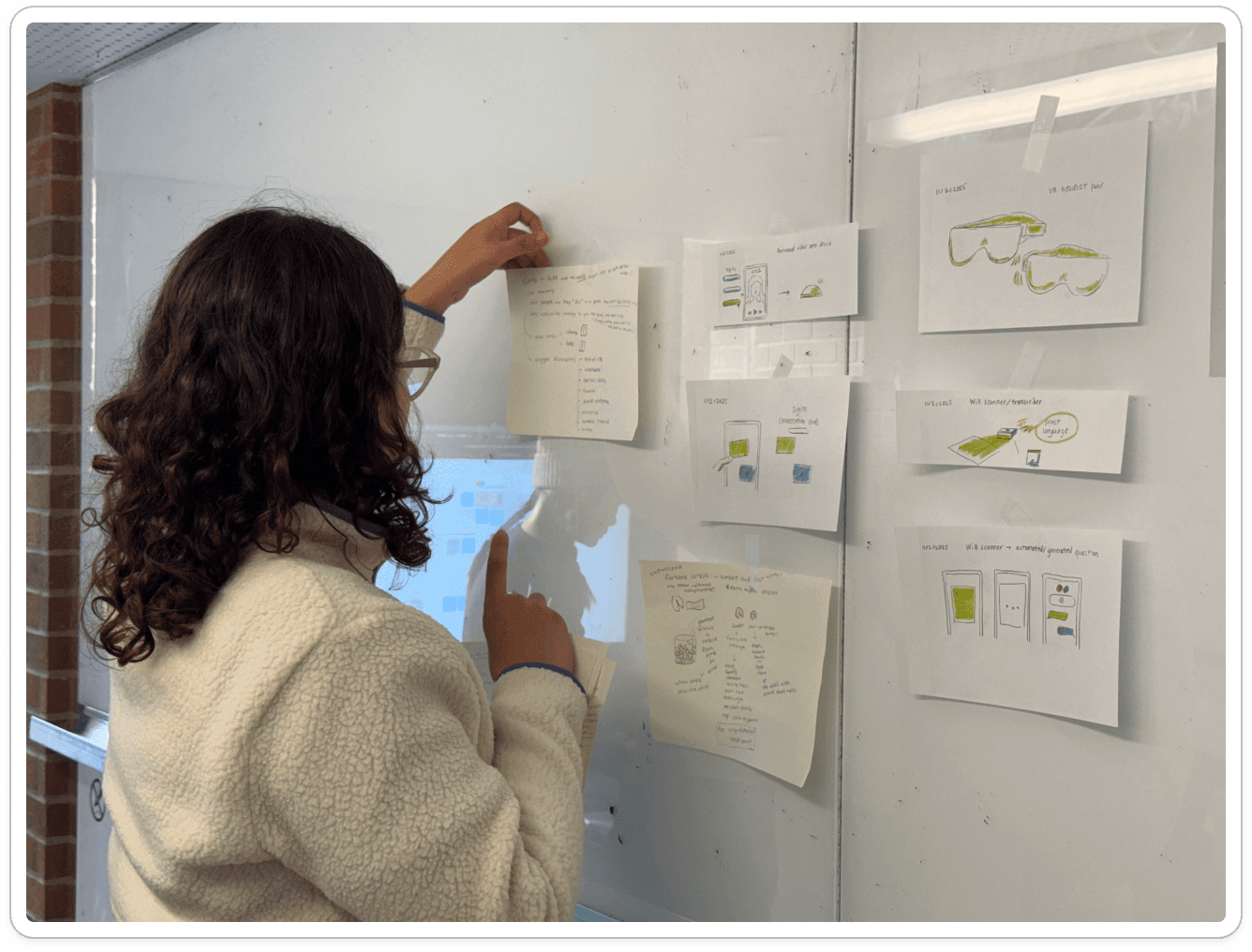 A teammate arranging paper sketches on a whiteboard.